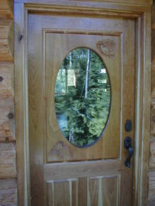 Custom cherry enrtry door with chickadees and pinecones carved in